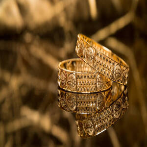 two bangles made of gold are put on a reflective surface