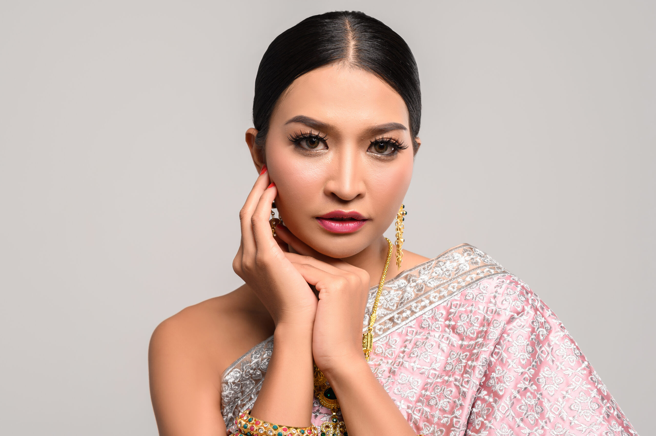 the girl wears thai dress and hands touch the face.